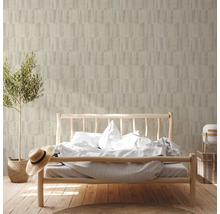 Slaapkamer met bed voor een muur met patroonbehang en een potplant.
