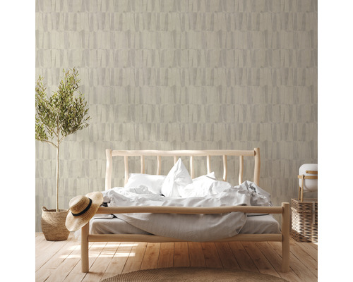 Slaapkamer met bed voor een muur met patroonbehang en een potplant.