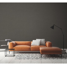 Moderne woonkamer met bruine bank, vloerkleed met geometrisch patroon en staande lamp.
