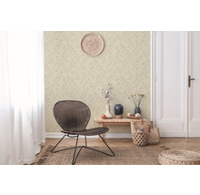 Woonkamer met patroonbehang, gevlochten stoel en decoratieve elementen voor een gezellige sfeer.