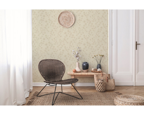 Woonkamer met patroonbehang, gevlochten stoel en decoratieve elementen voor een gezellige sfeer.