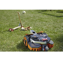 Robotmaaier op een gazon met speelgoed op de achtergrond