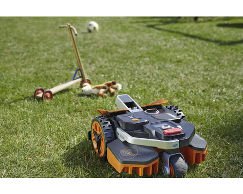 Robotmaaier op een gazon met speelgoed op de achtergrond