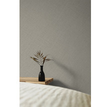 Close-up van een grijs vliesbehang met een fijn textielpatroon