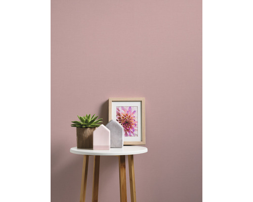 Decoratieve scène met potplant, fotolijst en huisdecoratie op een tafel voor een muur.