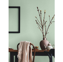 Lichte eetkamer met houten tafel, stoelen, decoraties en een fotolijst aan de muur