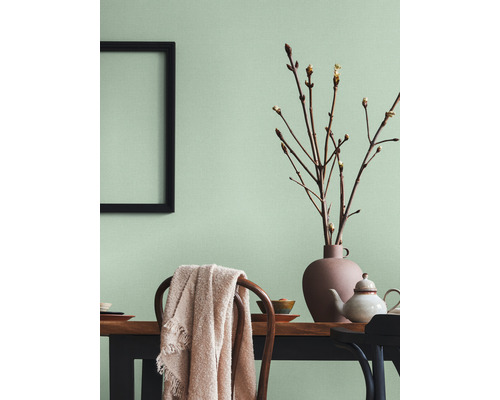 Lichte eetkamer met houten tafel, stoelen, decoraties en een fotolijst aan de muur