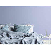 Slaapkamer met bed, kussens en bijzettafel