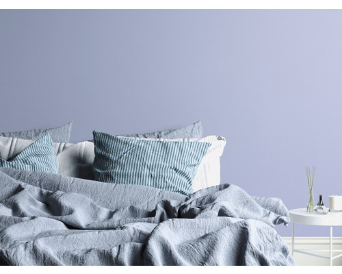 Slaapkamer met bed, kussens en bijzettafel