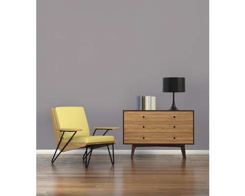 Woonkamer met fauteuil, dressoir, lamp en boeken op houten vloer