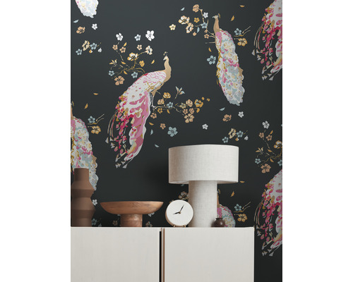 Woonkamer met een behang met pauwenmotieven, een tafellamp en decoratieve objecten op een dressoir.