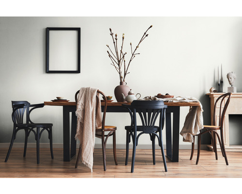 Eetkamer met houten tafel, stoelen en decoratieve elementen zoals vaas, servies en dekens.