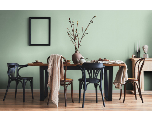 Eetkamer met houten tafel, stoelen en decoraties in een lichte ruimte.