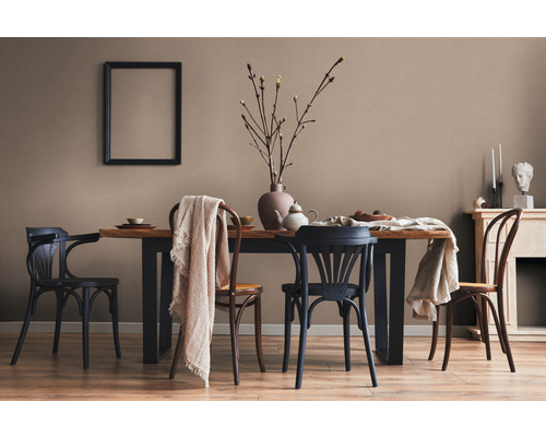 Eetkamer met houten tafel, stoelen, decoratie en een fotolijst aan de muur.