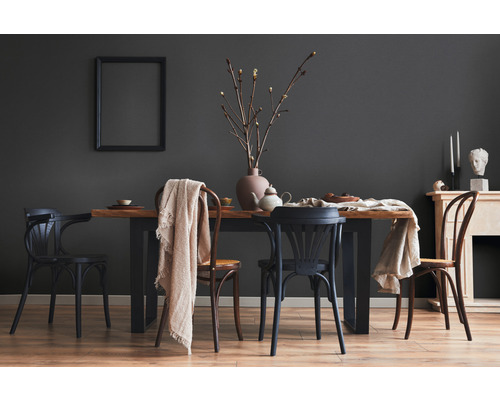 Eetkamer met houten tafel en stoelen voor een grijze muur