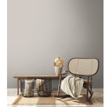 Woonkamer scène met houten bank, metalen manden, decoraties, vloerkleed en schommelstoel.