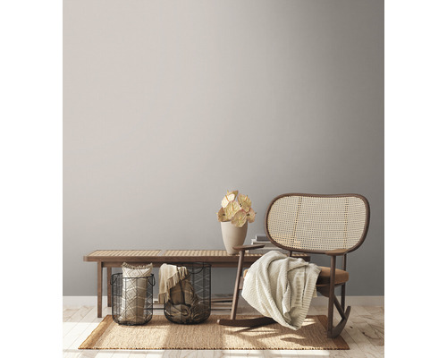 Woonkamer scène met houten bank, metalen manden, decoraties, vloerkleed en schommelstoel.