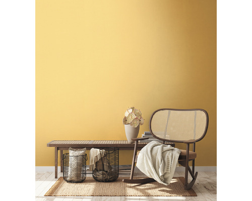 Woonkamer met houten bank, rotan schommelstoel en decoratie