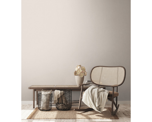 Woonkamerscène met bank, rotan schommelstoel, manden en decoratie op een vloerkleed.