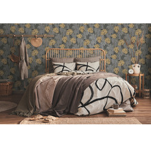Slaapkamer met bed voor een patroonbehang met plantmotieven.