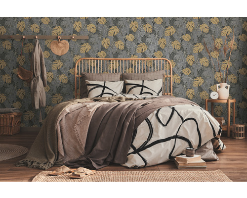 Slaapkamer met bed voor een patroonbehang met plantmotieven.