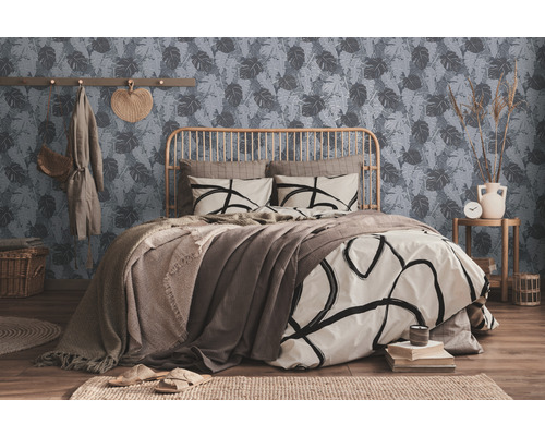 Een slaapkamer met een bed, een muur met een bladerpatroon en decoratieve elementen.