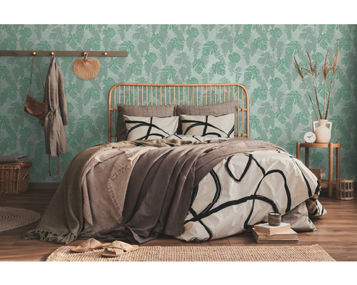 Lichte slaapkamer met bed voor een groen behang met bladeren