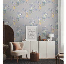 Lichte kamer met behang met pauwpatroon, fauteuil, dressoir en decoraties voor een huiselijke sfeer.