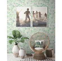 Decoratieve kamer met patroonbehang, rotan stoel, planten en ingelijste foto''s.