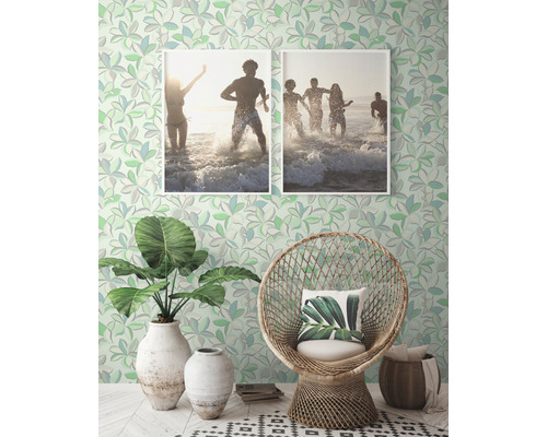 Decoratieve kamer met patroonbehang, rotan stoel, planten en ingelijste foto''s.