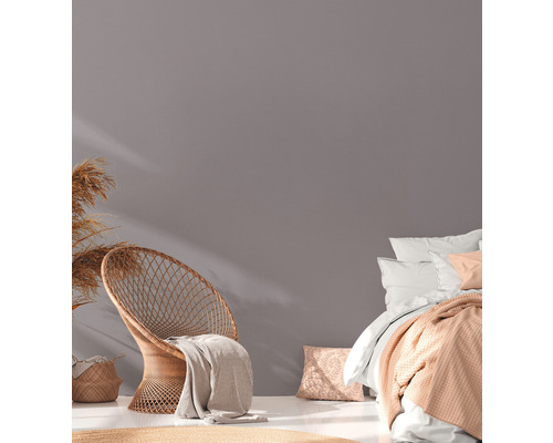 Lichte kamer met rotan stoel, bed en decoratie voor een gezellige sfeer.