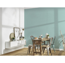 Eetkamer met houten tafel, stoelen en wandplank met decoraties tegen een gekleurde muur