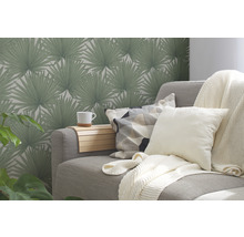 Woonkamer met grijze bank, kussens, deken en behang met palmmotief