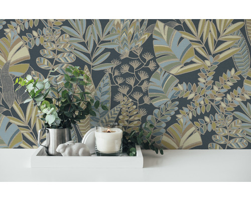 Decoratieve opstelling met behang met bladerpatroon, kaars, planten en decoraties op een witte tafel