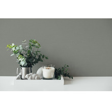 Decoratieve opstelling met kaars, plant en decoratief figuur op een dienblad.