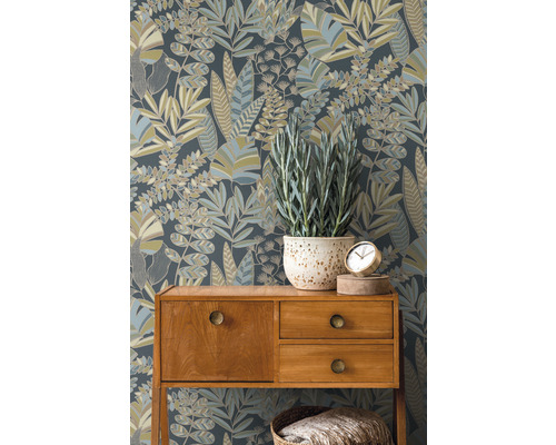 Decoratief behang met plantmotieven achter een commode met potplant en klok