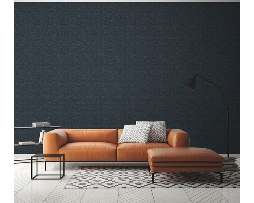 Woonkamer met oranje lederen bank, hocker, boekenplank, vloerlamp en behang met motief