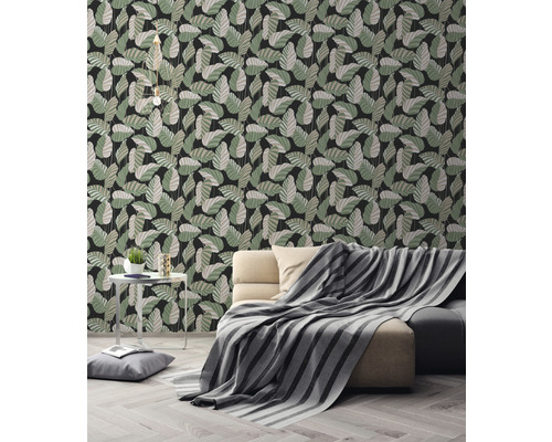 Woonkamer met bank en behang met bladerpatroon.