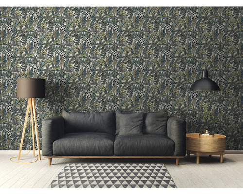 Woonkamer met behang met bladerpatroon, bank, vloerlamp, tapijt en bijzettafel.