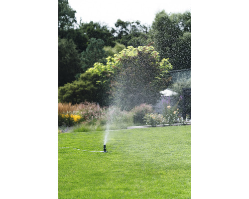 Tuinscene met gazonsproeier die een groene omgeving besproeit