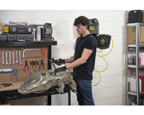 Man pompt opblaaskrokodil op op een werkbank met gereedschap