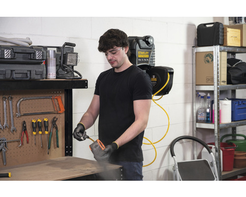 Man reinigt een filter met perslucht in een werkplaats met gereedschap en een persluchtslanghaspel