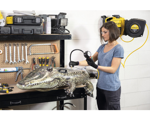 Vrouw pompt opblaasbare alligator op met luchtmanometer op werkbank.
