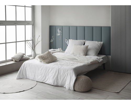 Lichte slaapkamer met bed, kussens en blauw hoofdeinde met vogelmotief