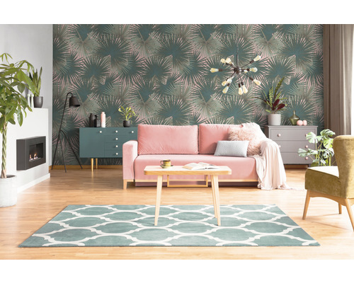 Woonkamer met palmbladerenbehang, bank, tapijt en meubels.