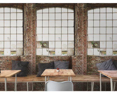 Interieur met bakstenen muur en grote ramen, evenals tafels en zitplaatsen.