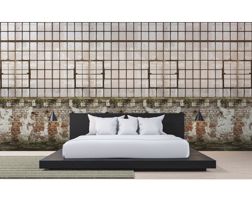 Slaapkamer met een bed voor een bakstenen muur en grote ramen