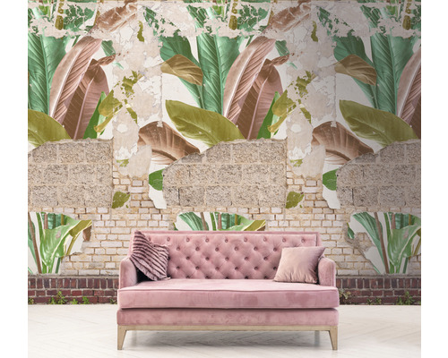 Roze bank voor een muur met behang met bladerpatroon en blootliggend metselwerk