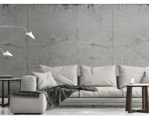 Woonkamer met bank, bijzettafel en vloerlamp tegen een betonnen muur