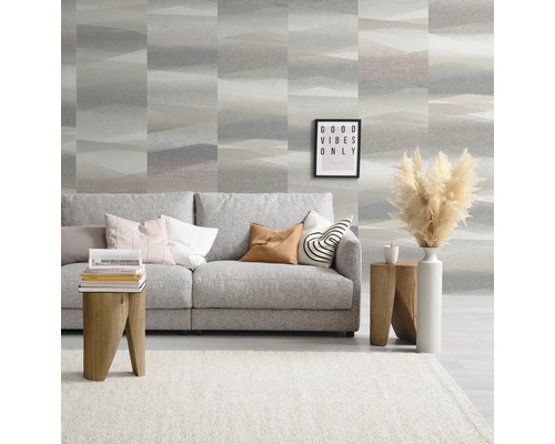 Woonkamer met grijze bank, houten kruk en patroonbehang